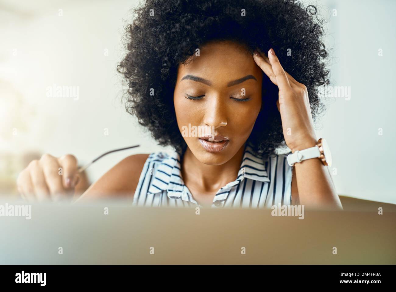 This headache is not helping my creative process. a young female designer experiencing a headache in a modern office. Stock Photo