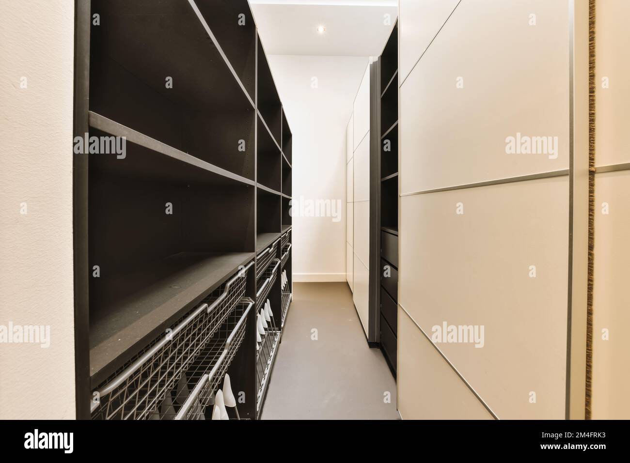 a long narrow hallway with black and white on either sides, leading to an open door