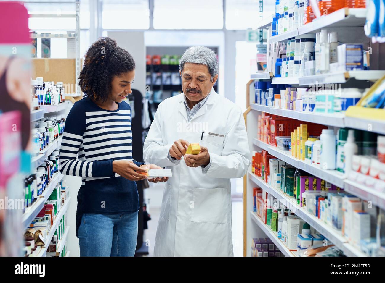 This is one of the best products on the market. a pharmacist assisting a young woman in a chemist. Stock Photo