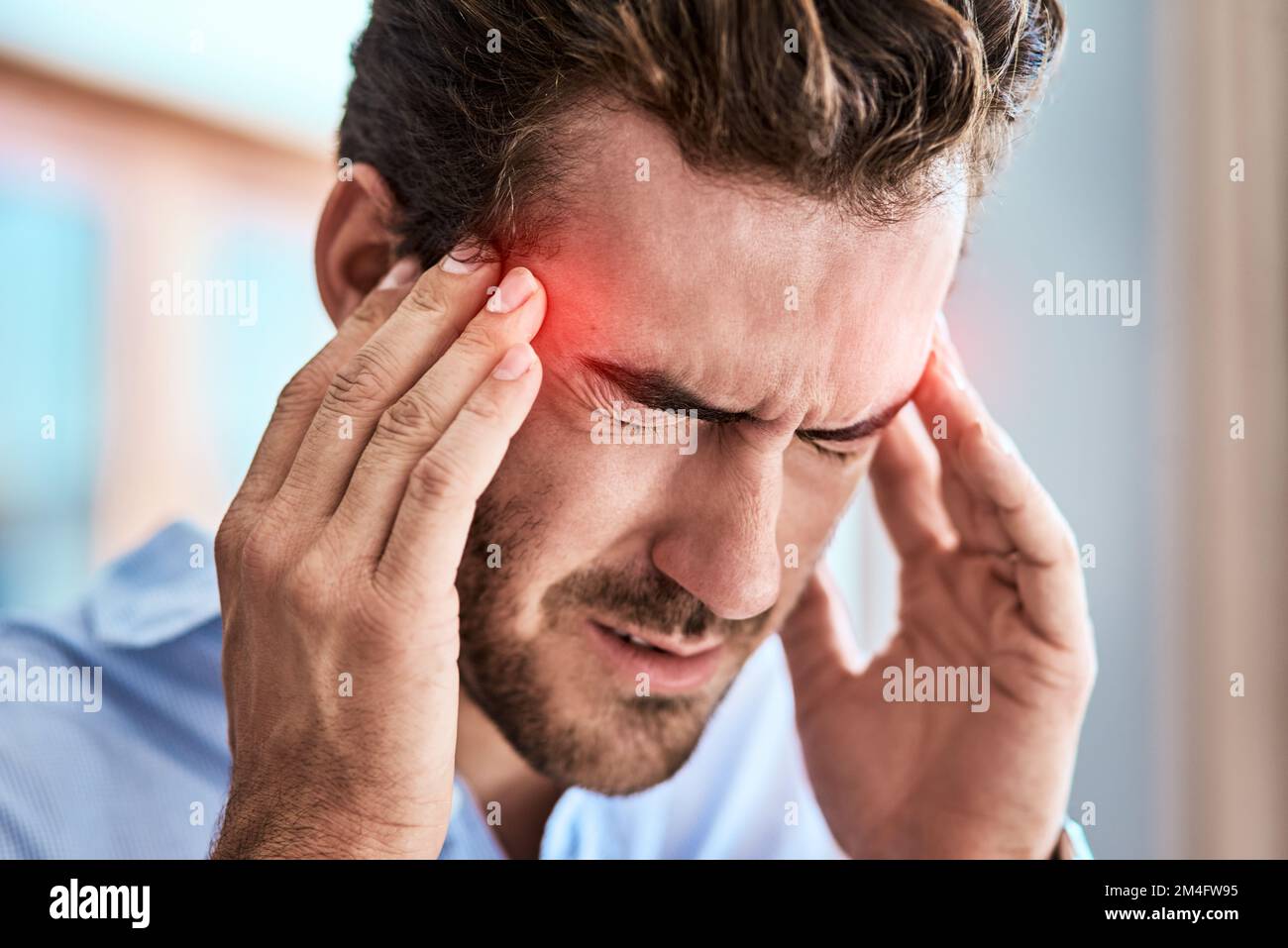 I need to take something for this headache. a uncomfortable looking man holding his head in discomfort due to pain at home during the day. Stock Photo