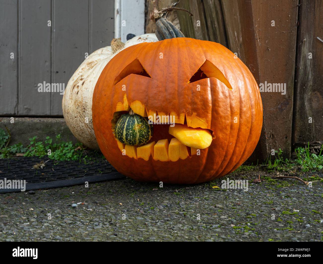 Pumpkin carved into a sinister looking face for Halloween on a UK doorstep Stock Photo