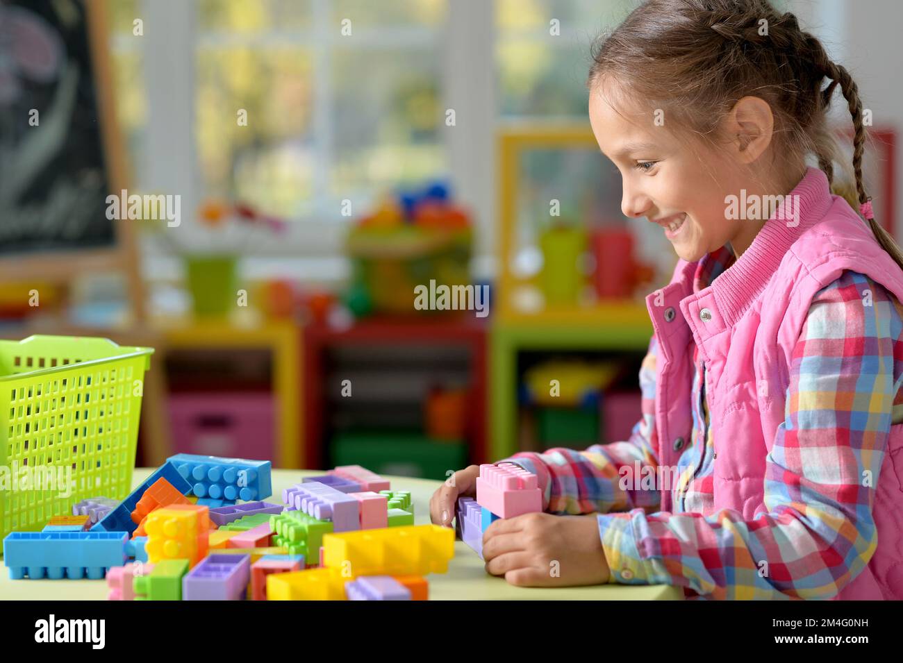 little girl playing with colorful plastic blocks at home Stock Photo ...