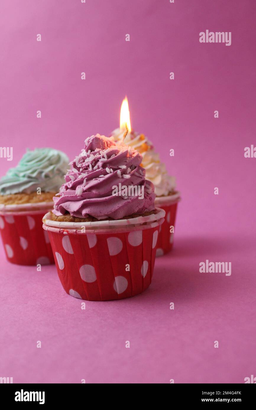 cake cupcake basket with a cap of cream pink lilac with a burned candle. Anniversary 1 year holiday birthday with space for text pink background Stock Photo