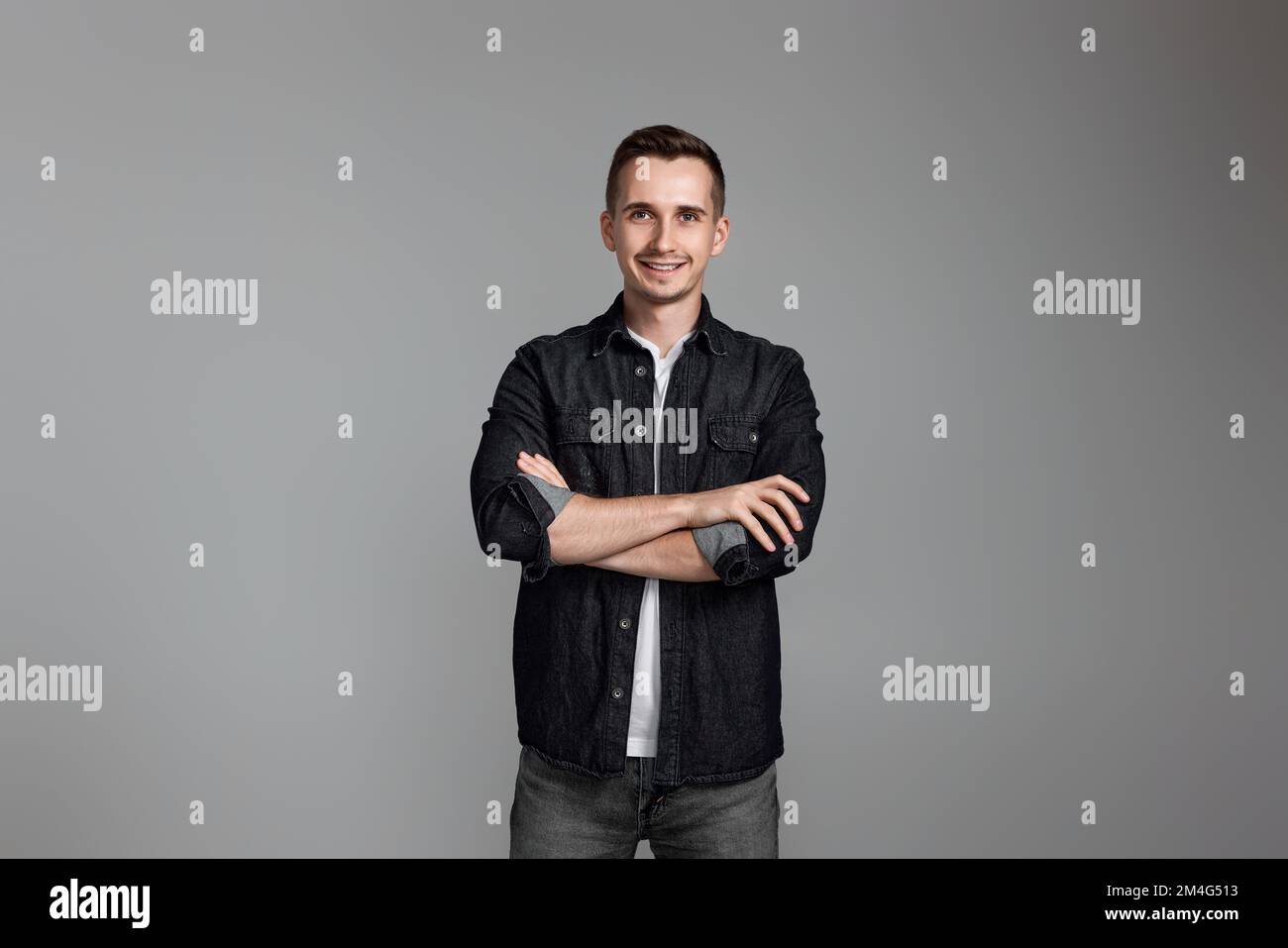 smiling young guy posing with crossed arms Stock Photo