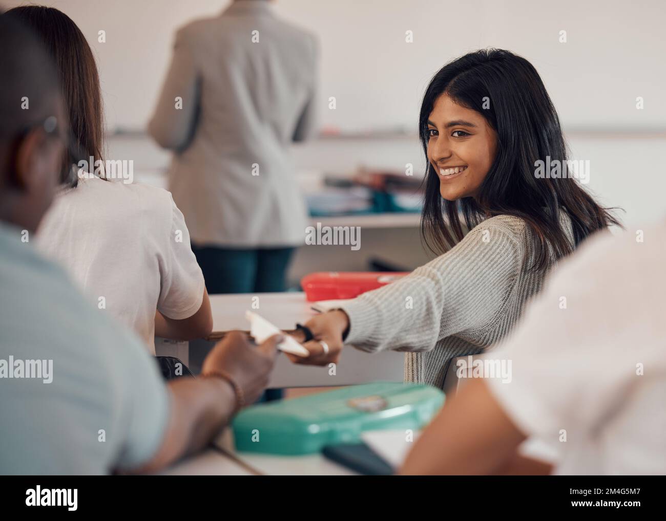 University, note and students cheating in exam passing paper notes in classroom. College corruption, education fraud and teamwork of woman helping man Stock Photo