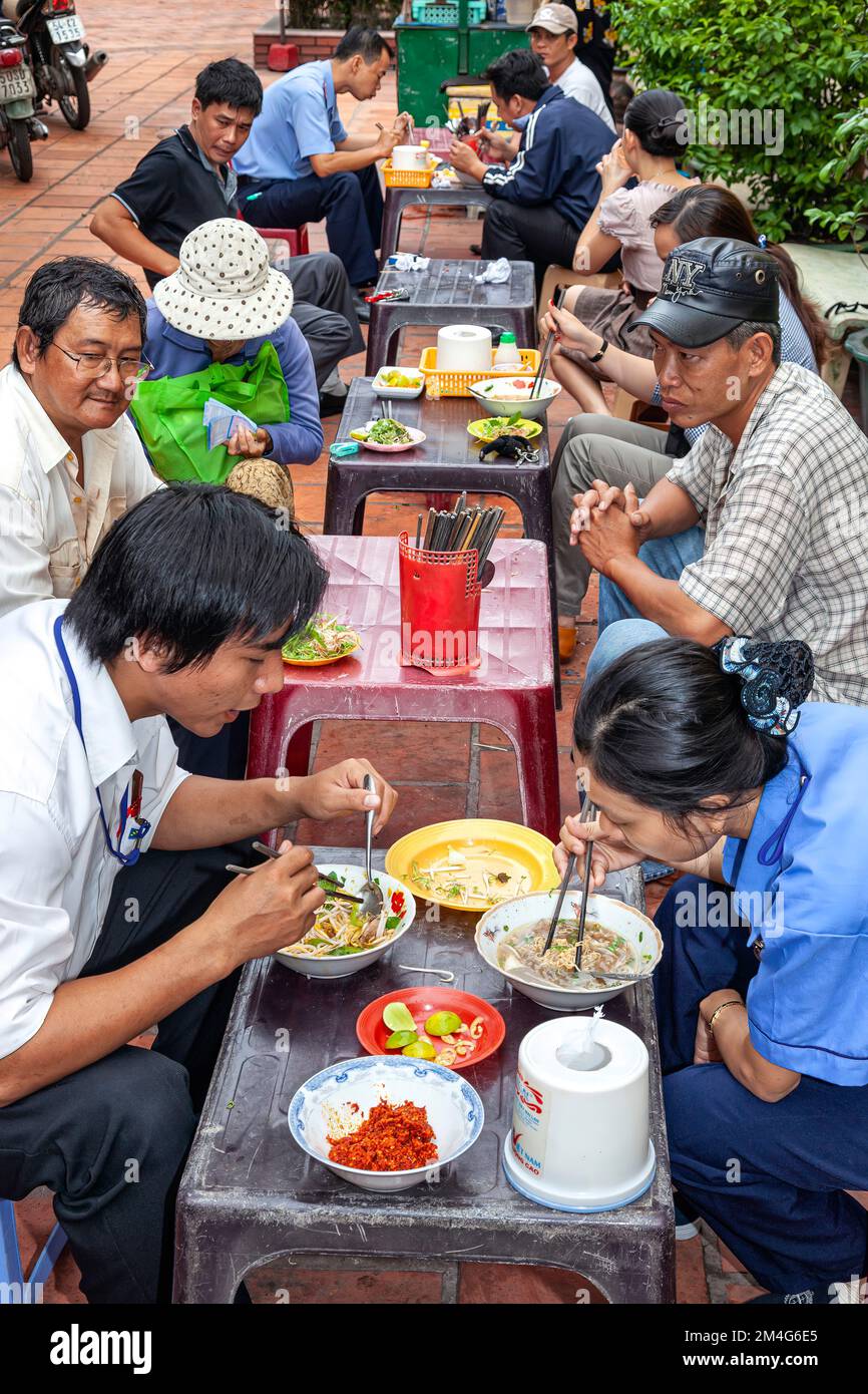 Vietnamese people eating at open air street restaurant, Ho Chi Minh City, Vietnam Stock Photo