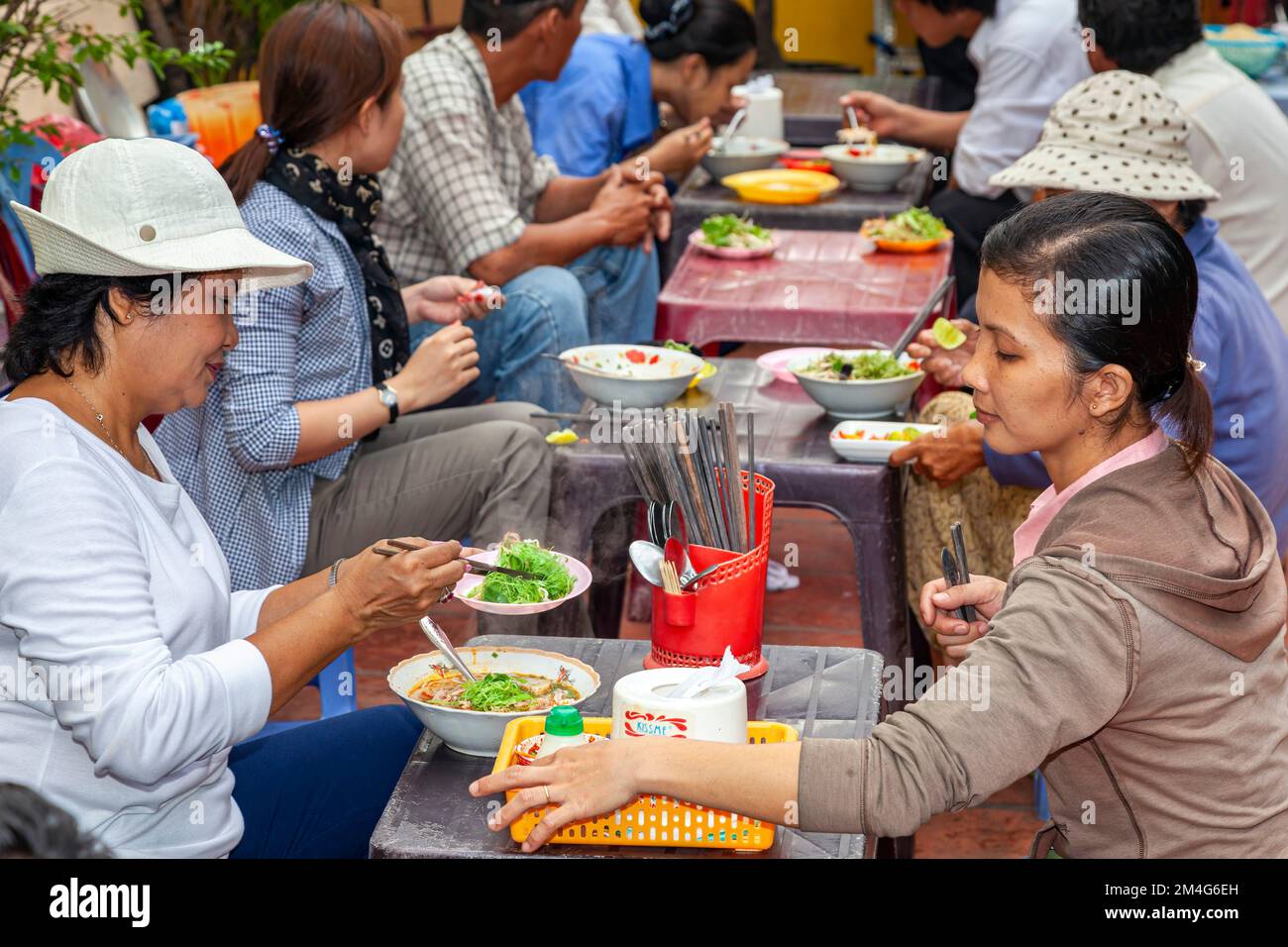 Vietnamese people eating at open air street restaurant, Ho Chi Minh City, Vietnam Stock Photo
