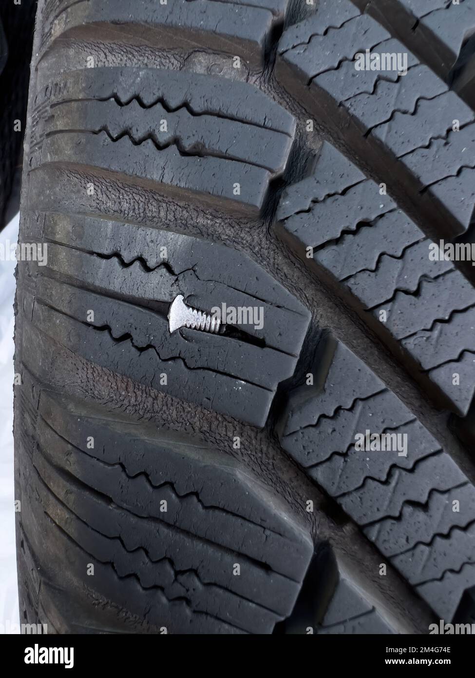 Button head needle metal nail stuck to puncture into wheel tire - winter flat tire flat Stock Photo