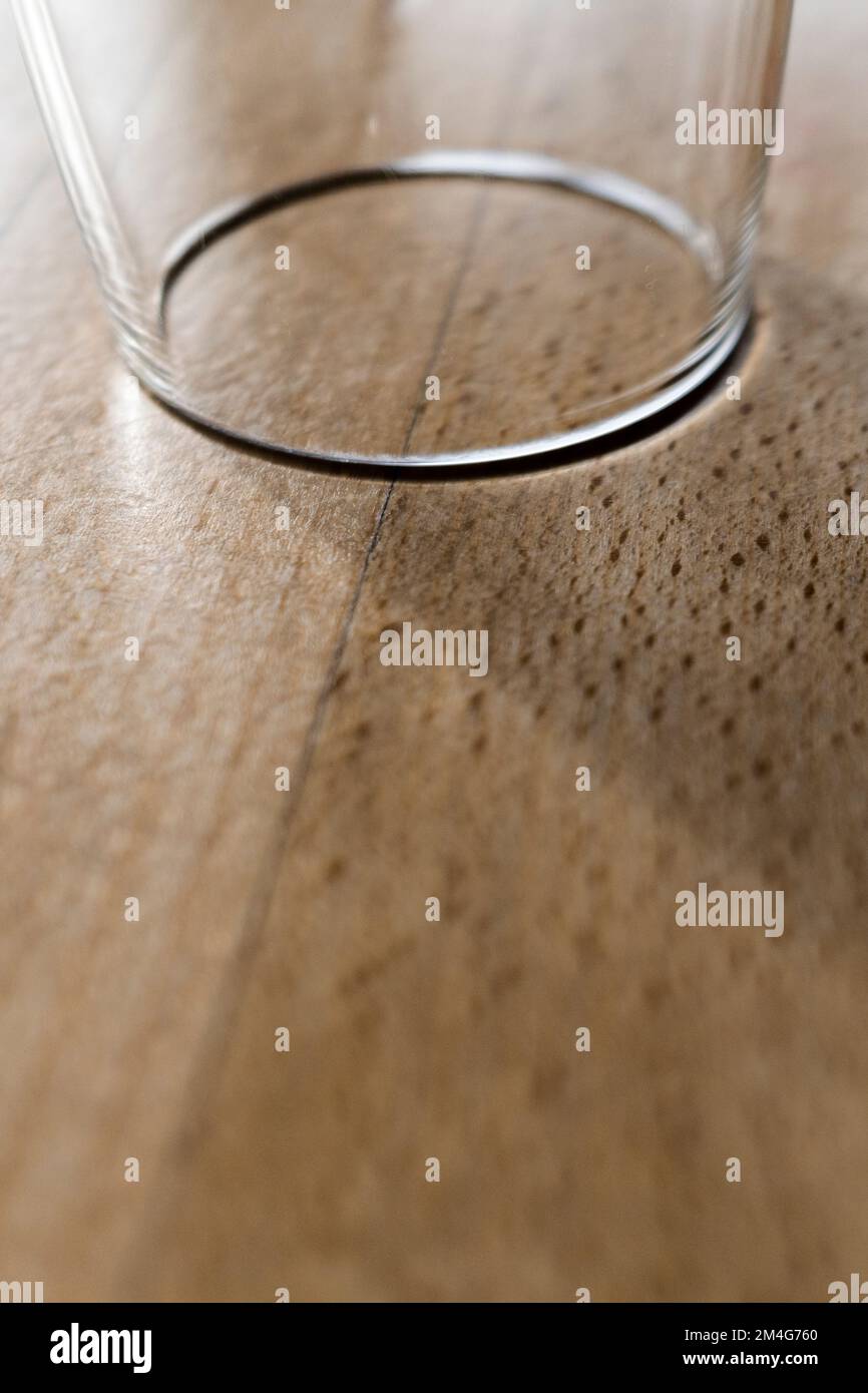 A closeup view of an unused clean glass tumbler upside down on a table. Stock Photo