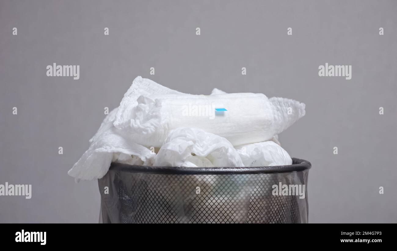 Person throws dirty diapers into loaded bin and changes clean diapers