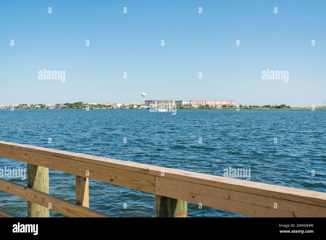 Views of buildings against the clear sky from a pier with wood handrails in Destin, Florida