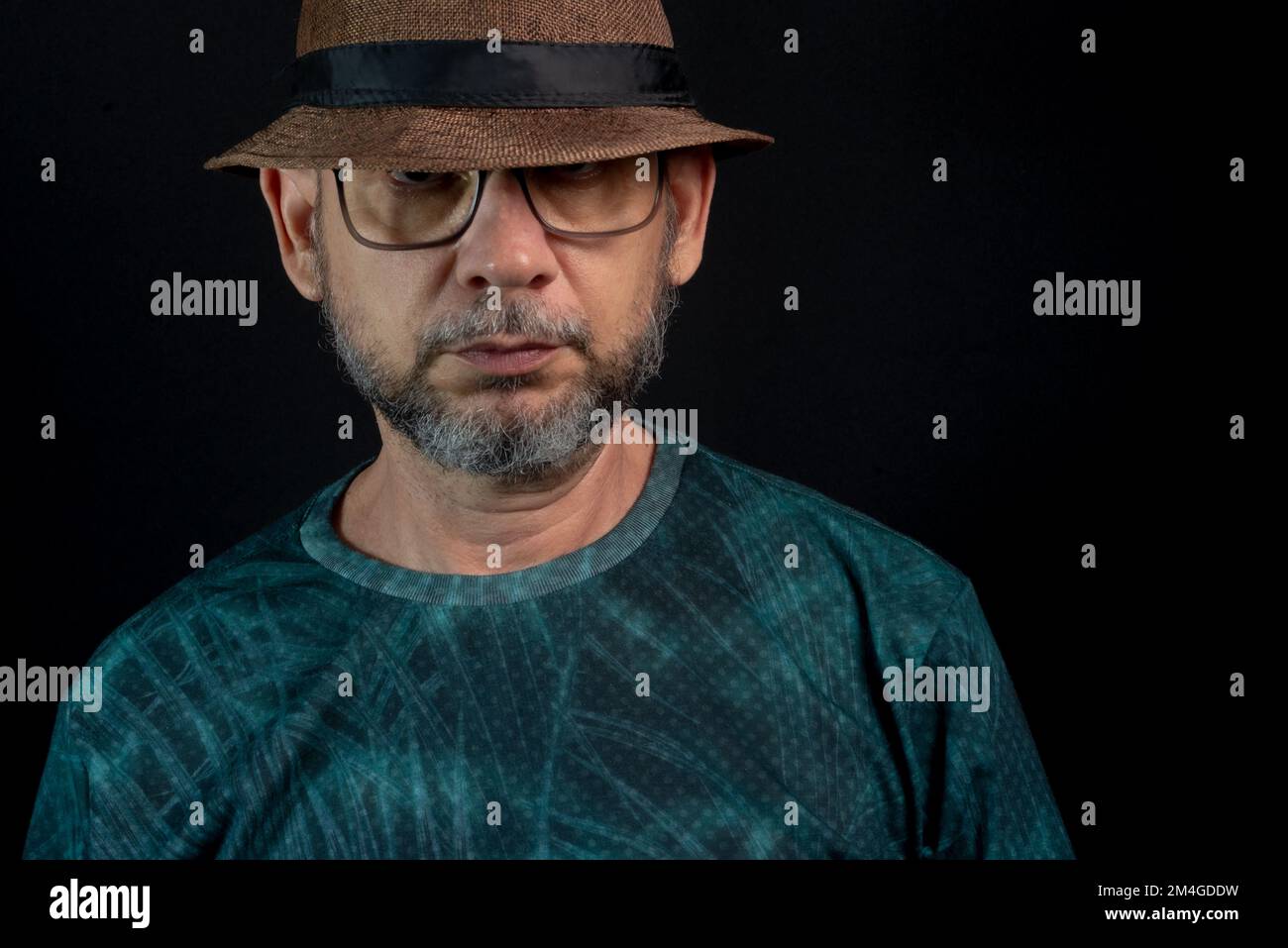 Portrait of a man wearing a hat and glasses. Looking at the camera. Isolated on black background. Stock Photo