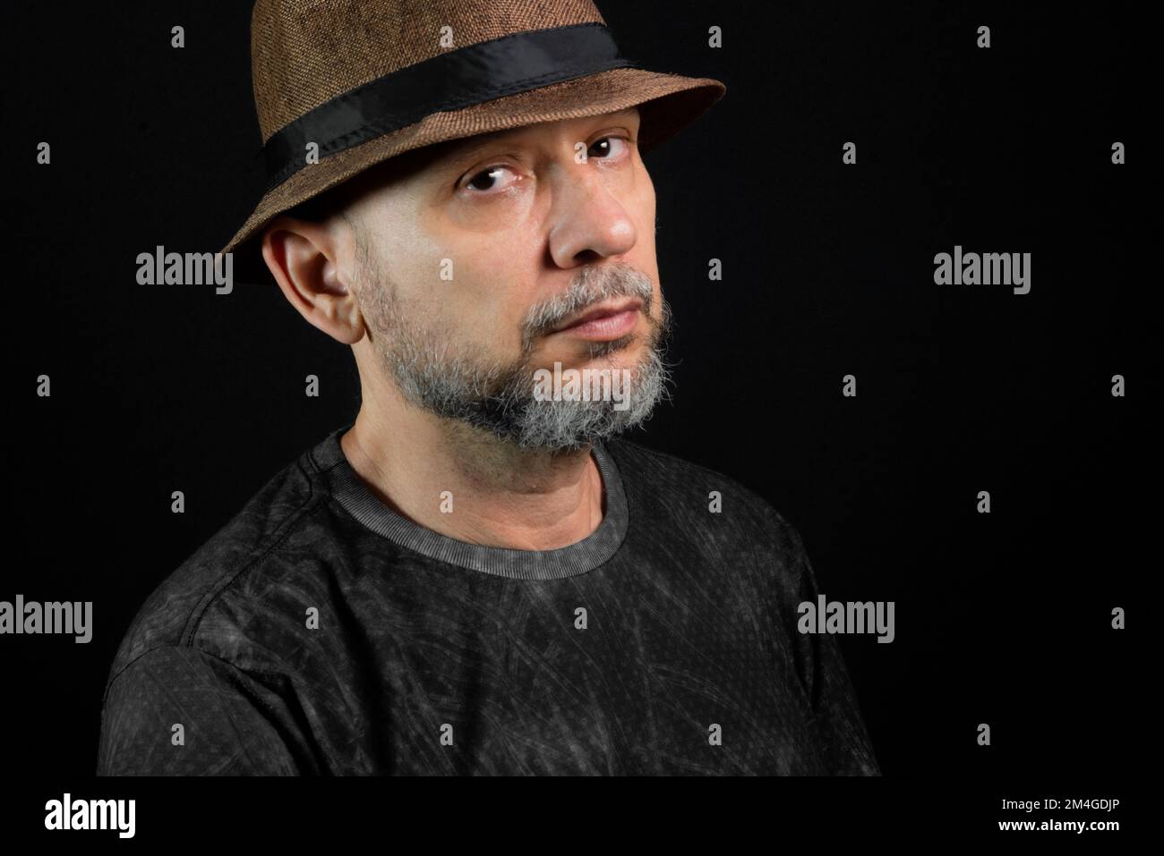 Portrait of a man wearing a hat and glasses. Looking at the camera. Isolated on black background. Stock Photo