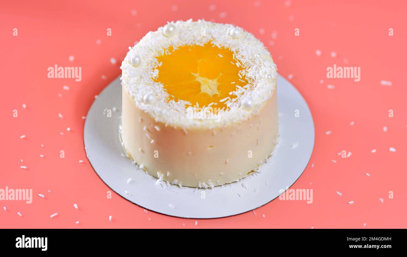 Cake with orange and coconut shavings spun on a pink background Stock Photo