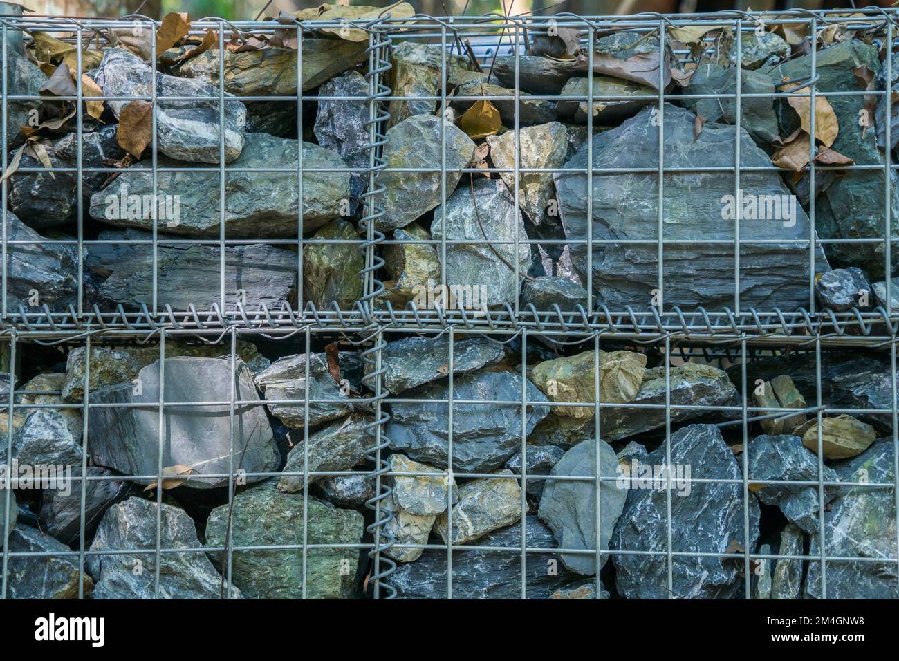 Decorative fence of bulk stone in the grid. Textured background of a stone wall with iron