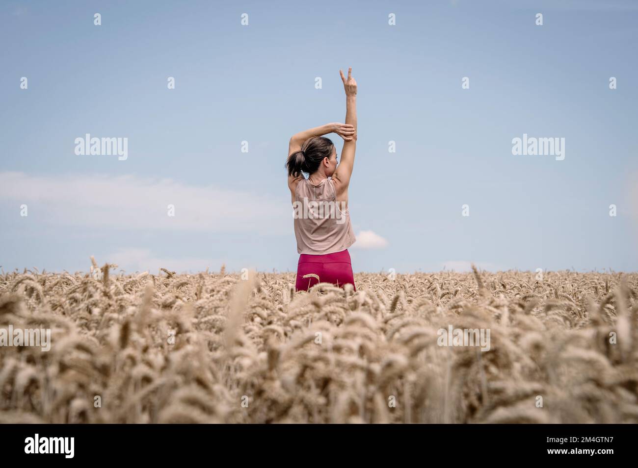 Rear view of a woman with her arms raised with a V sign. Getting away from it all concept. Stock Photo