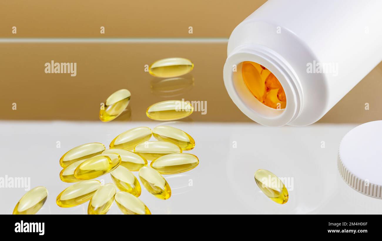 Natural pills, vitamins or supplements on glass shelf on beige background. White bottle with healthy supplements in gel capsules. Omega 3, fish oil or Stock Photo