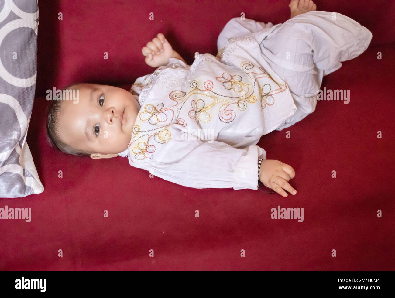 infant boy in traditional indian outfit lying on sofa cute facial expression at indoor Stock Photo