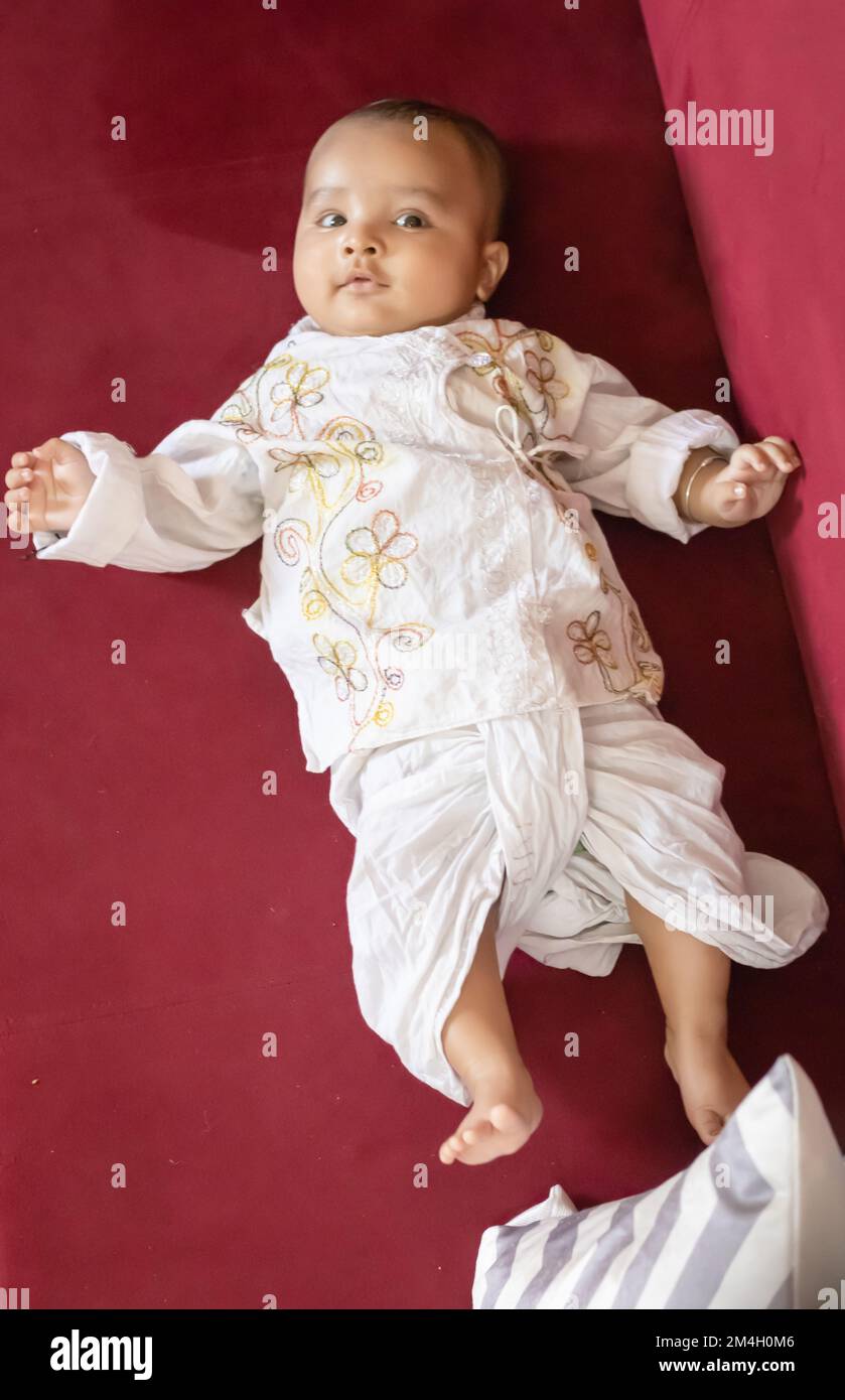 infant boy in traditional indian outfit lying on sofa cute facial expression at indoor Stock Photo