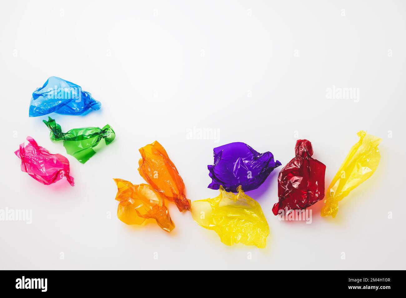 Colorful candy wrappers on white. Sugar sweets concept. Abstract background with copy space