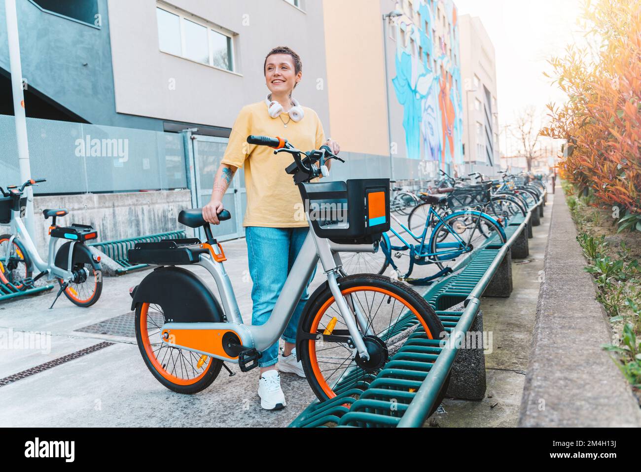 Woman takes a rented bicycle in a bicycle parking Stock Photo