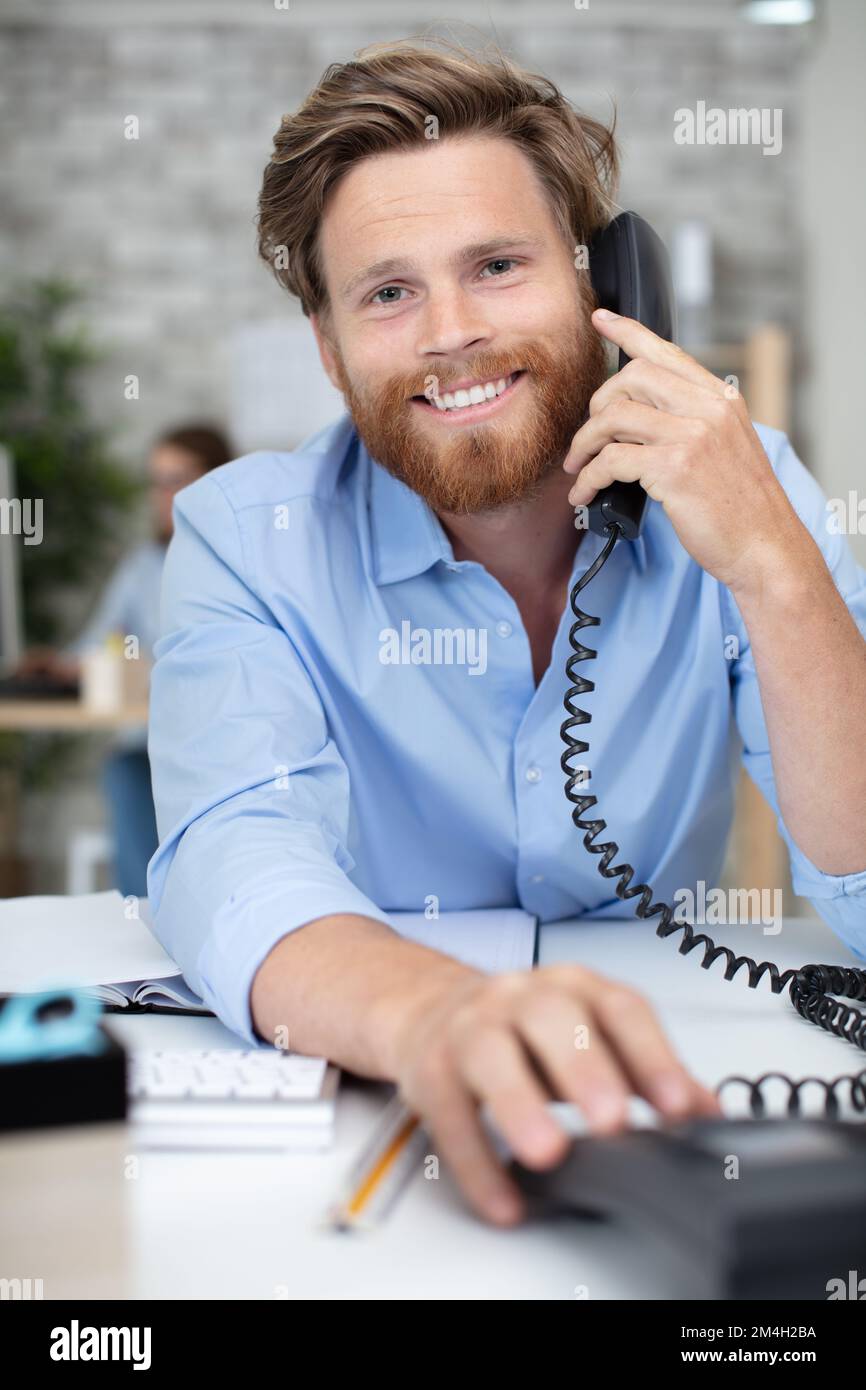 happy entrepreneur at his desk in office talking over telephone Stock