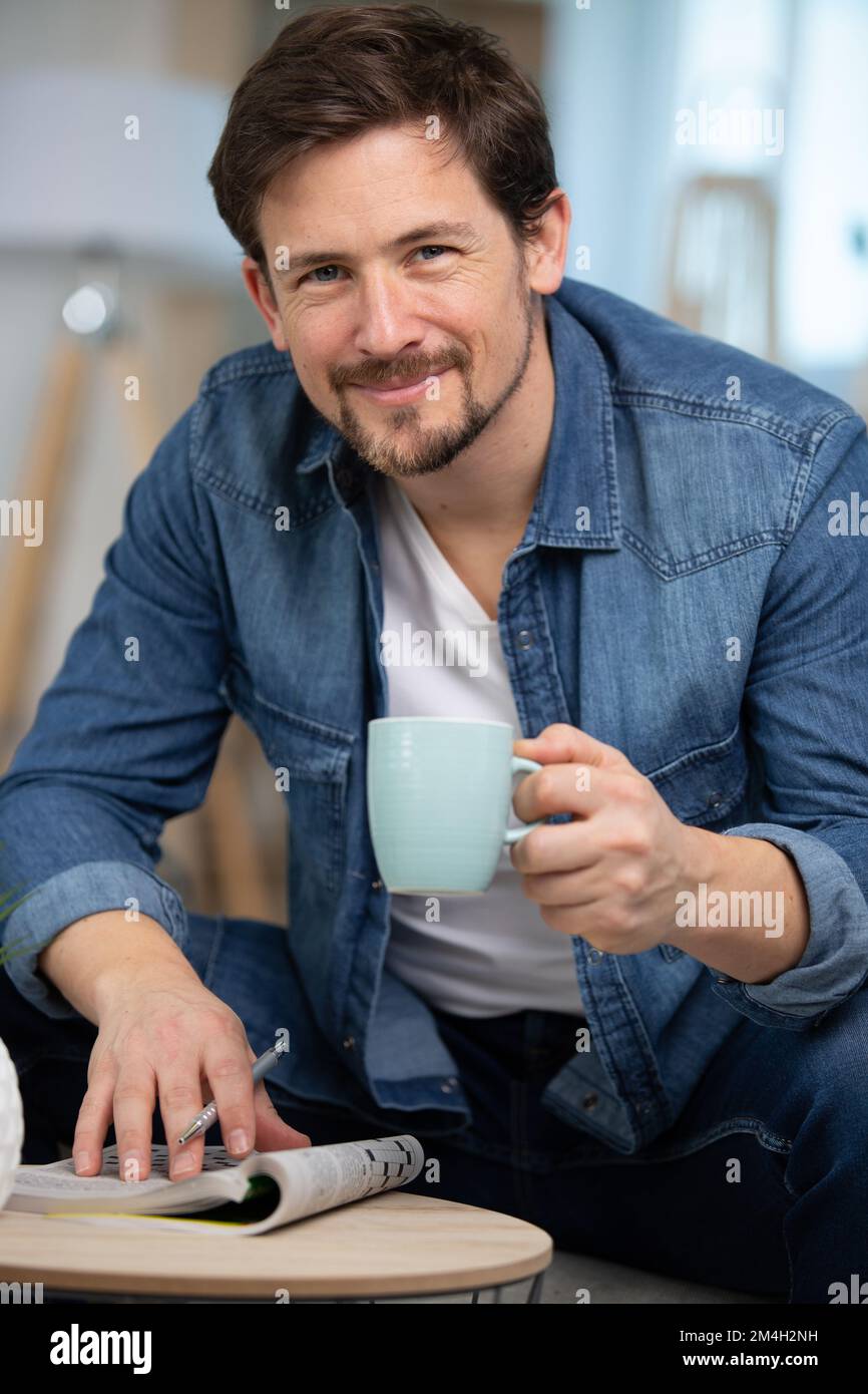 man doing crossword and drinking coffee Stock Photo Alamy
