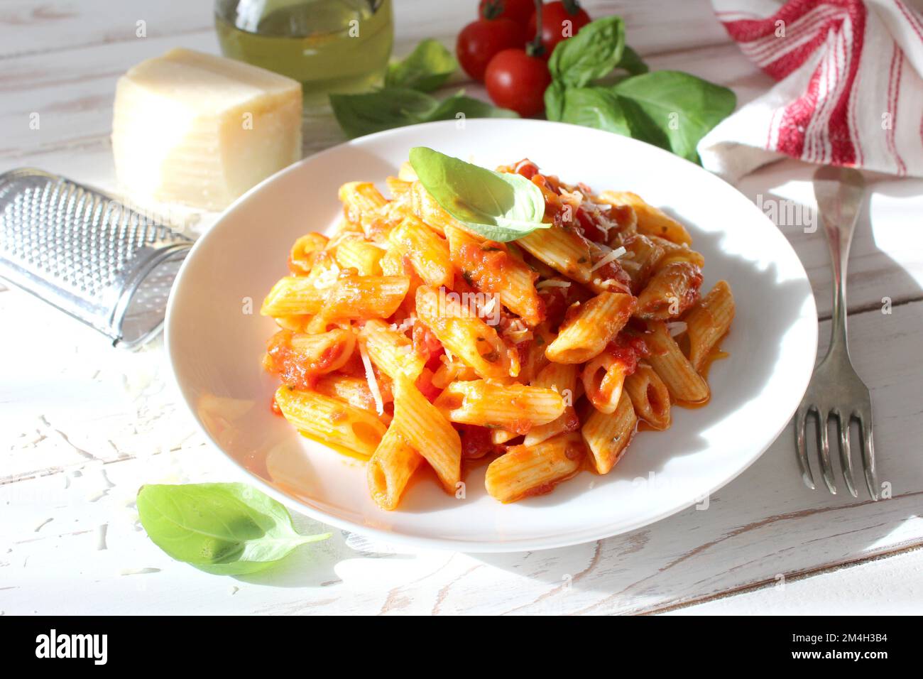 Penne pasta with tomato sauce, parmesan cheese and basil. Top view with