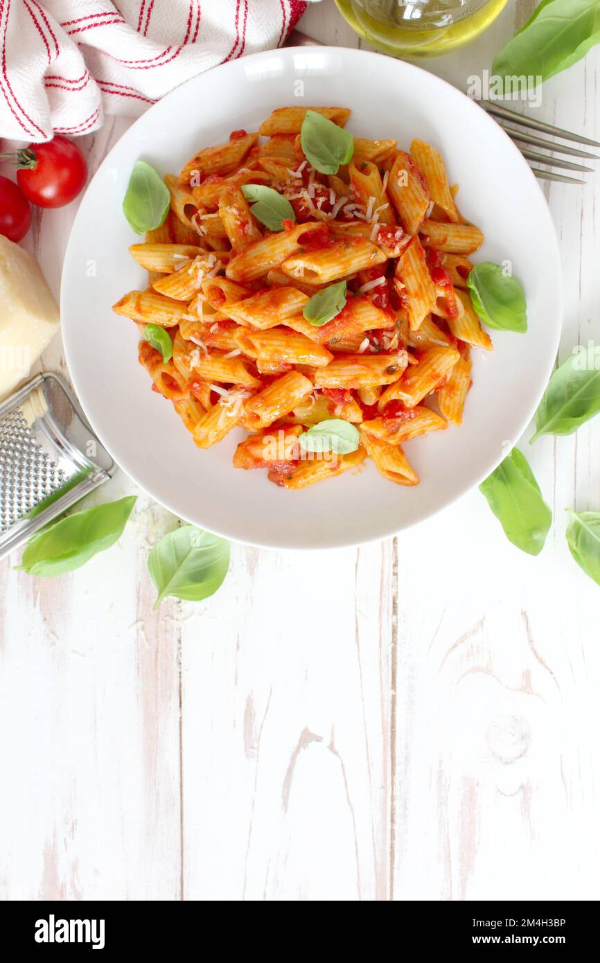 Penne pasta with tomato sauce, parmesan cheese and basil. Top view with