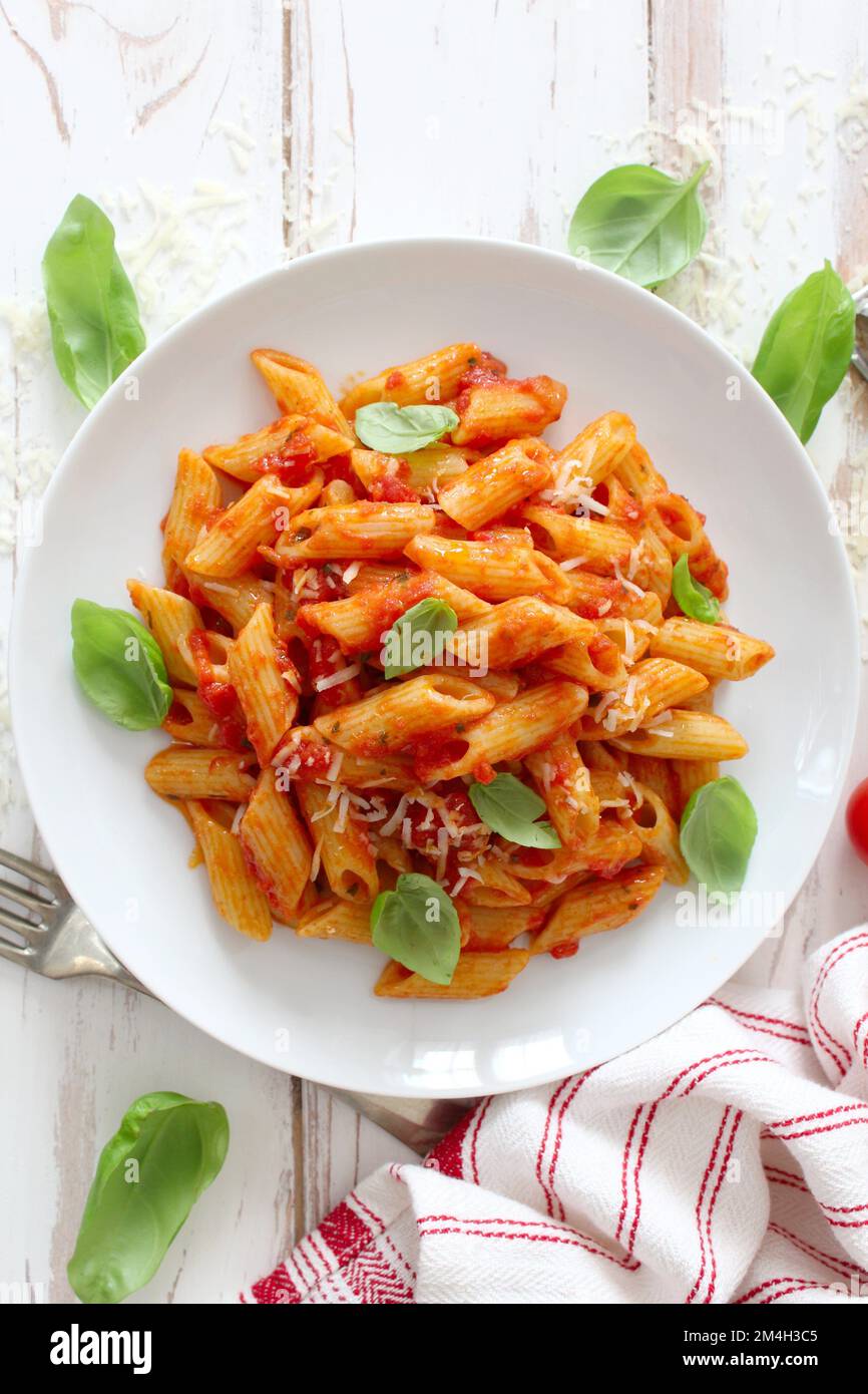 Penne pasta with tomato sauce, parmesan cheese and basil. Top view with