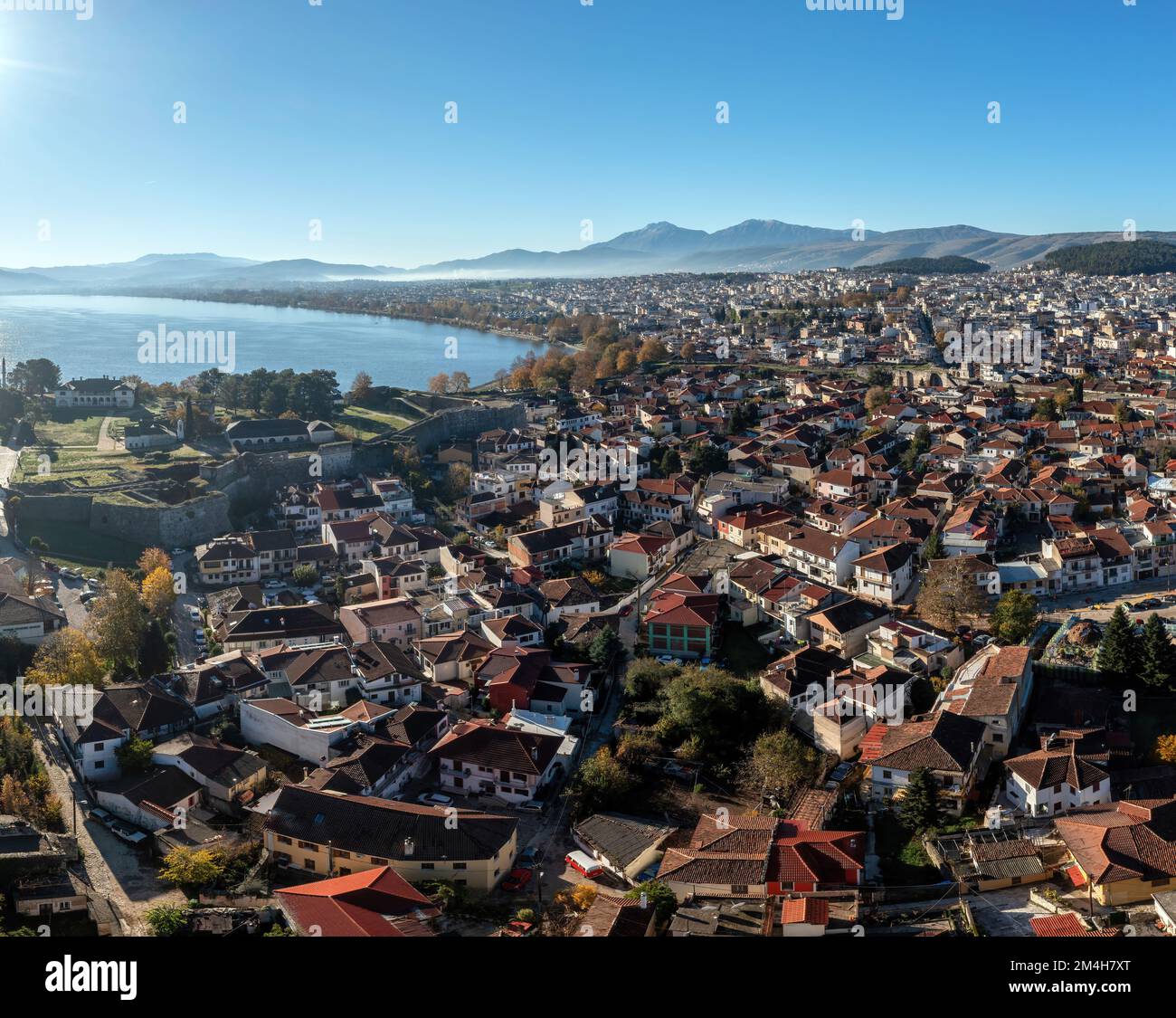 Greece, Ioannina Pamvotida Lake, Epirus. Aerial drone view of Giannena city red tile roof buildings, blue sky background. Stock Photo