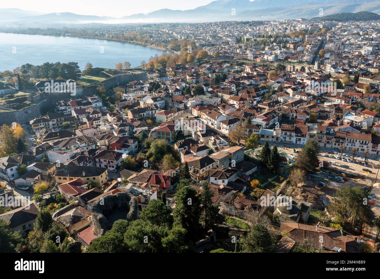 Greece, Ioannina Pamvotida Lake, Epirus. Aerial drone view of Giannena city red tile roof buildings, blue sky background. Stock Photo
