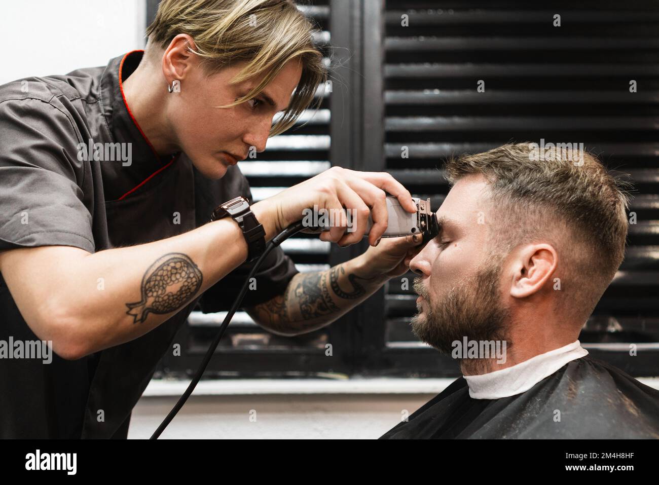 Barber woman trims eyebrows to man in barber shop male salon Stock