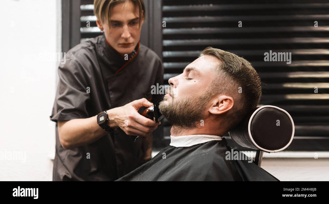 Trimming beard in the Barber woman cutting beard to man
