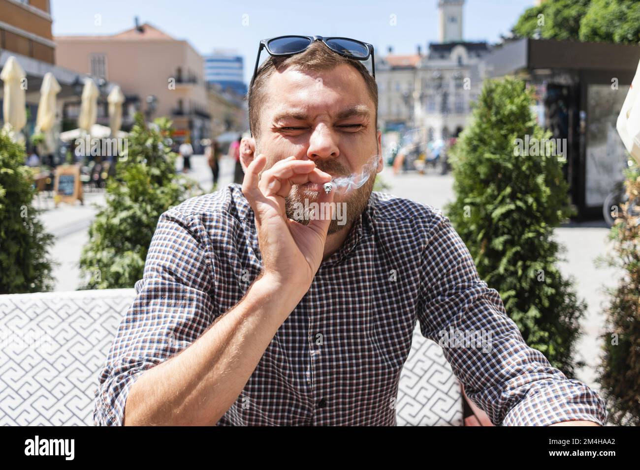 Man smoking cigarette with disgusting in cafe outdoors. Stock Photo