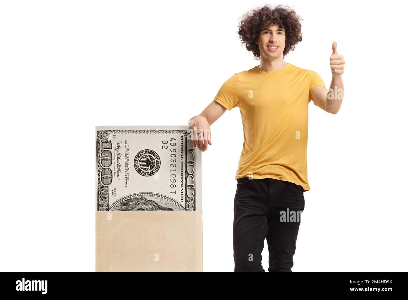 Young man with curly hair leaning on a stack of money and showing thumbs up isolated on white background Stock Photo