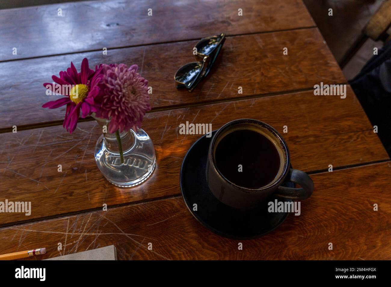 cup of coffee wooden table in the background vase with purple flowers in the background vegetation Stock Photo