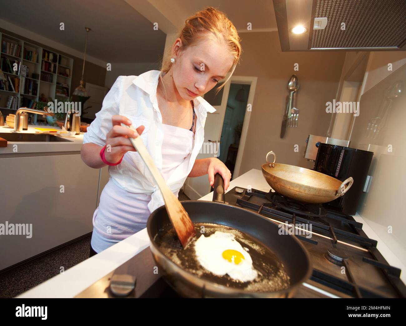 Netherlands, girl is frying an egg in the kitchen Stock Photo