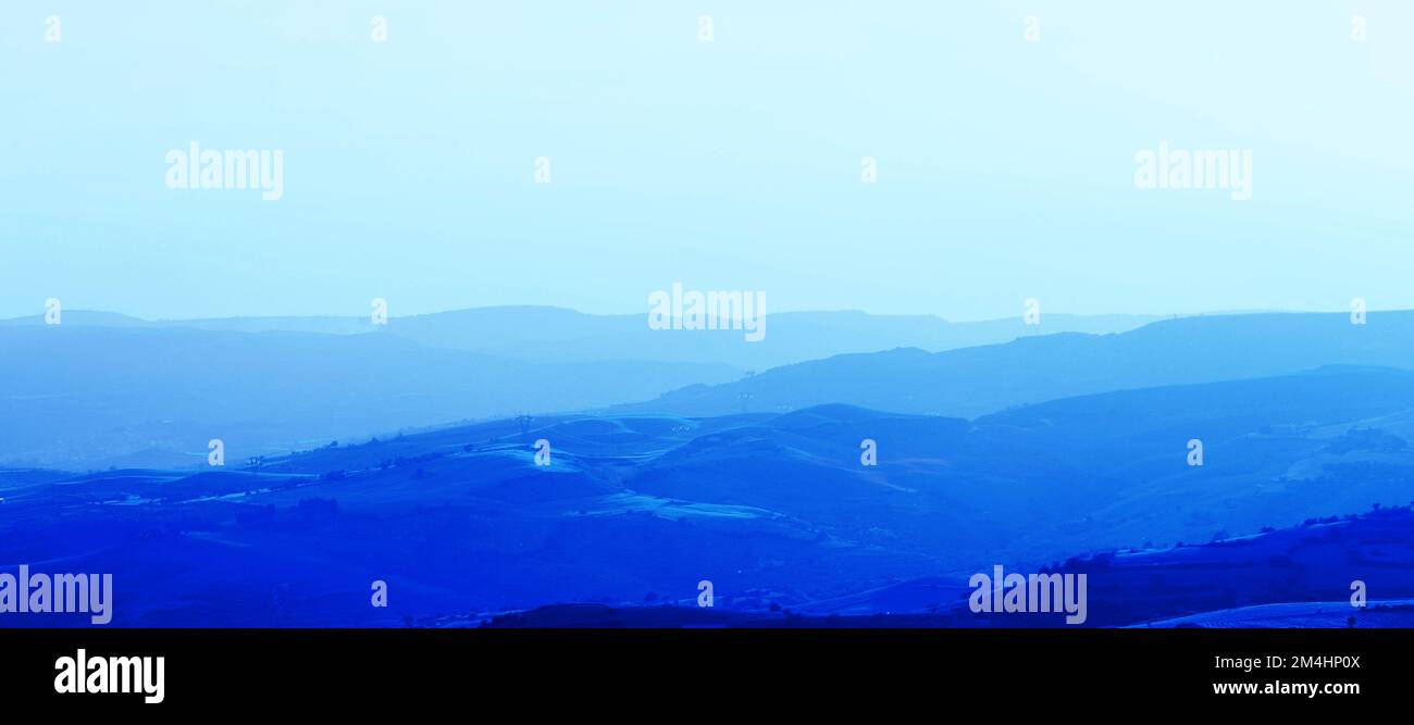 Layers of mountain ranges stacked in blue silhouette.Aerial perspective