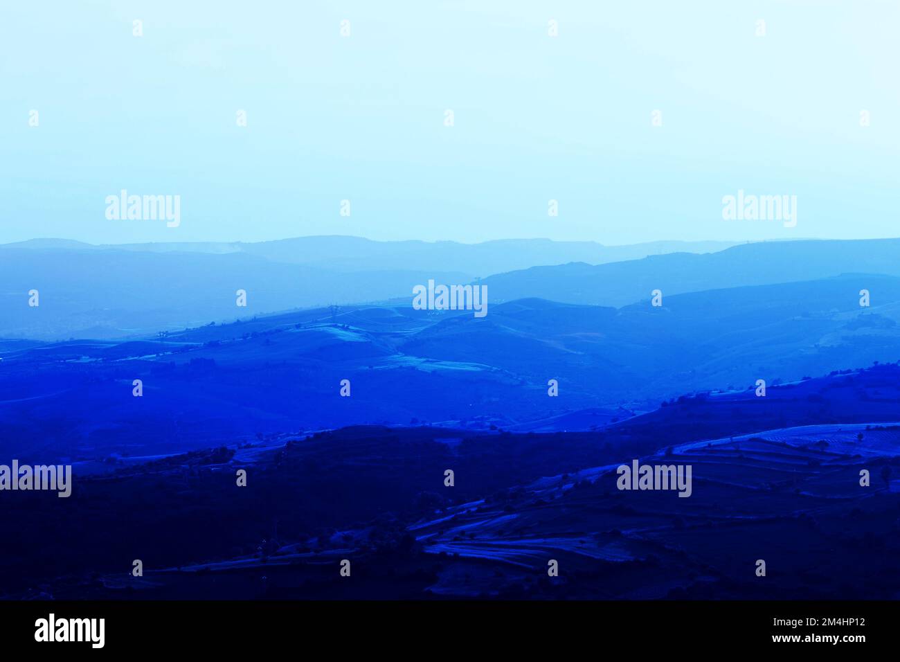Layers of mountain ranges stacked in blue silhouette.Aerial perspective