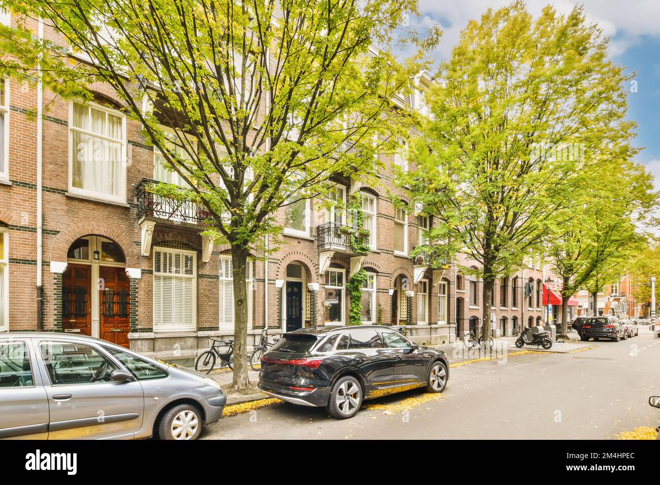 a city street with cars parked on the curbs and trees in front of ...