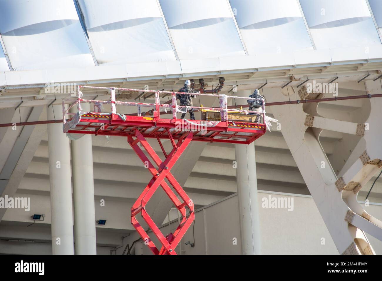 Construction workers standing in the scissors lifting crane bucket ...
