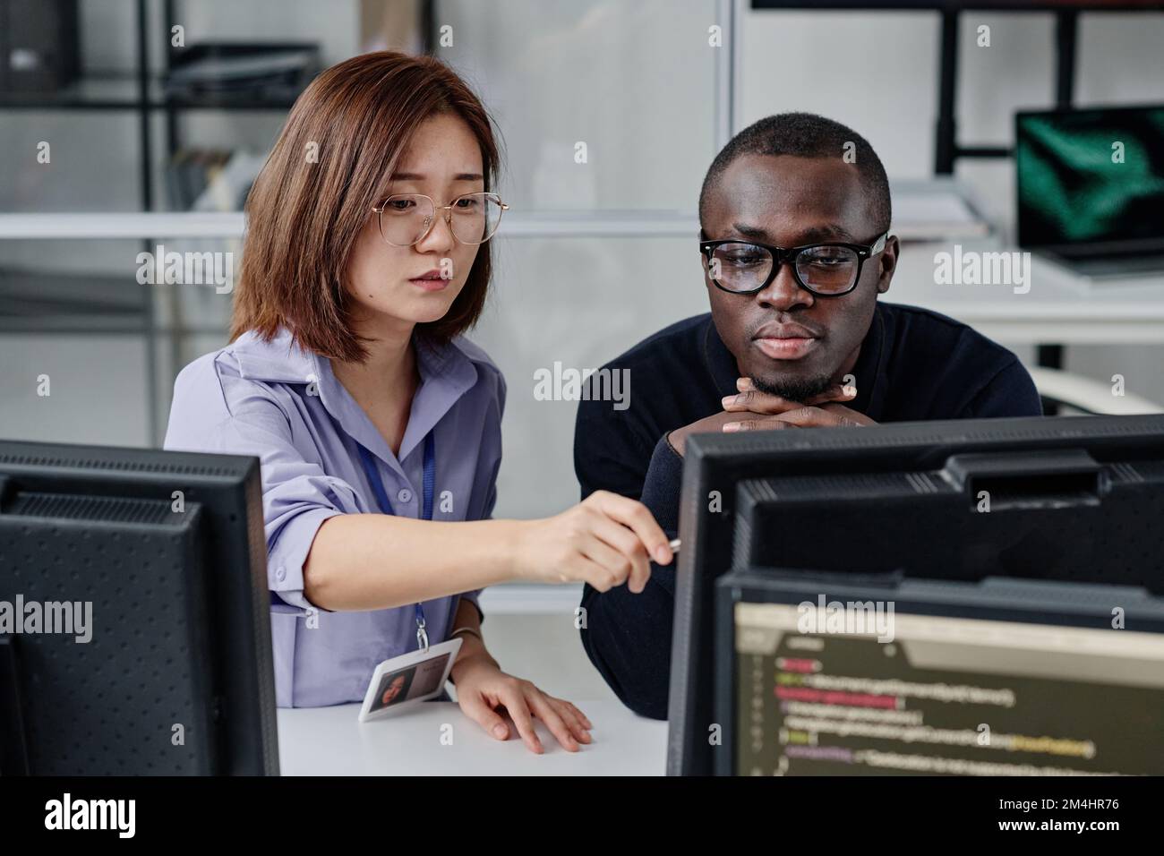Multiethnic couple of developers working on computer together to develop new program Stock Photo