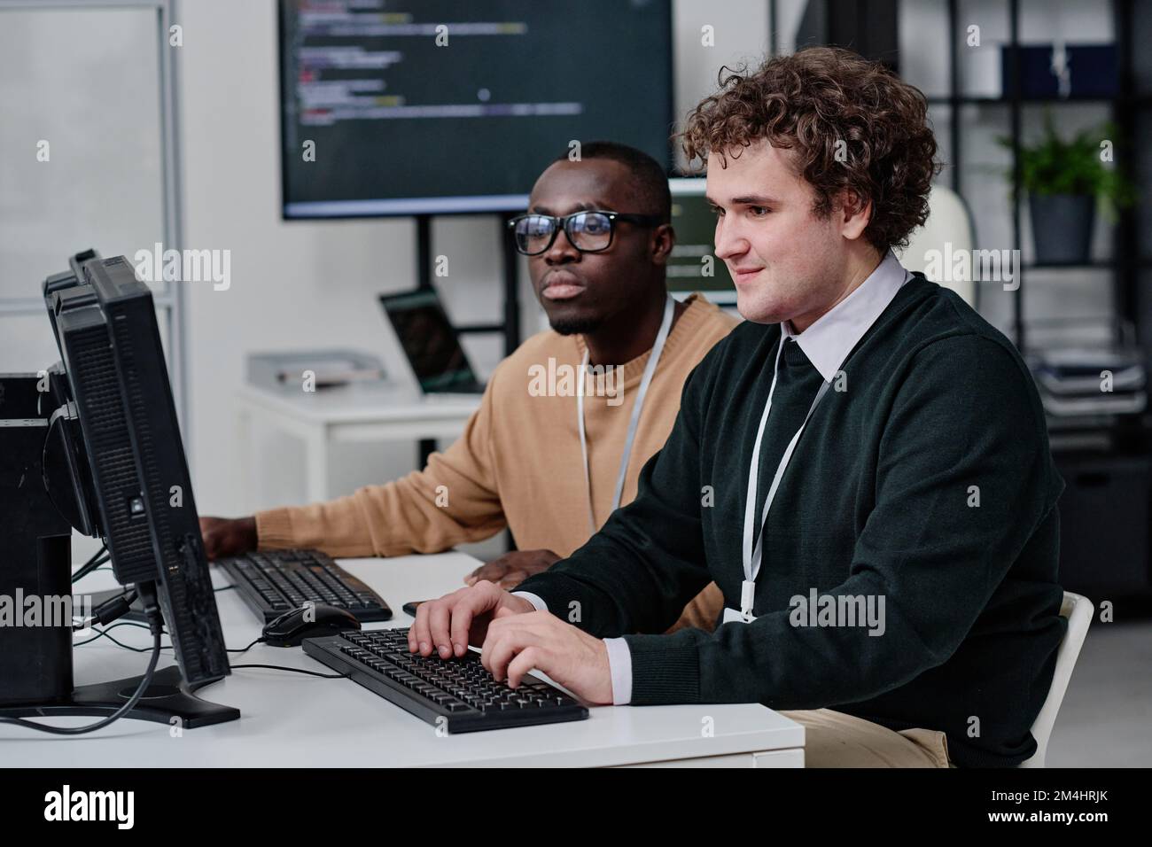Two IT specialists working together with computer codes for new software on computer during teamwork in office Stock Photo