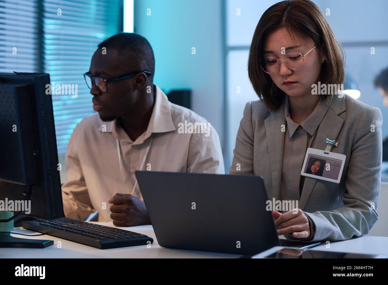 Two young colleagues sitting at table and working on computers with computer program Stock Photo