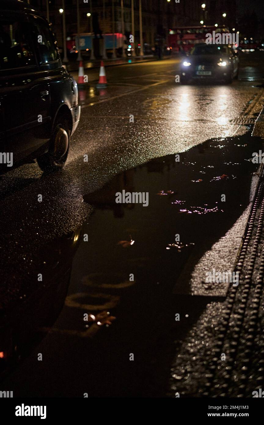 Blurred background with London black cab on wet road with large puddle Stock Photo