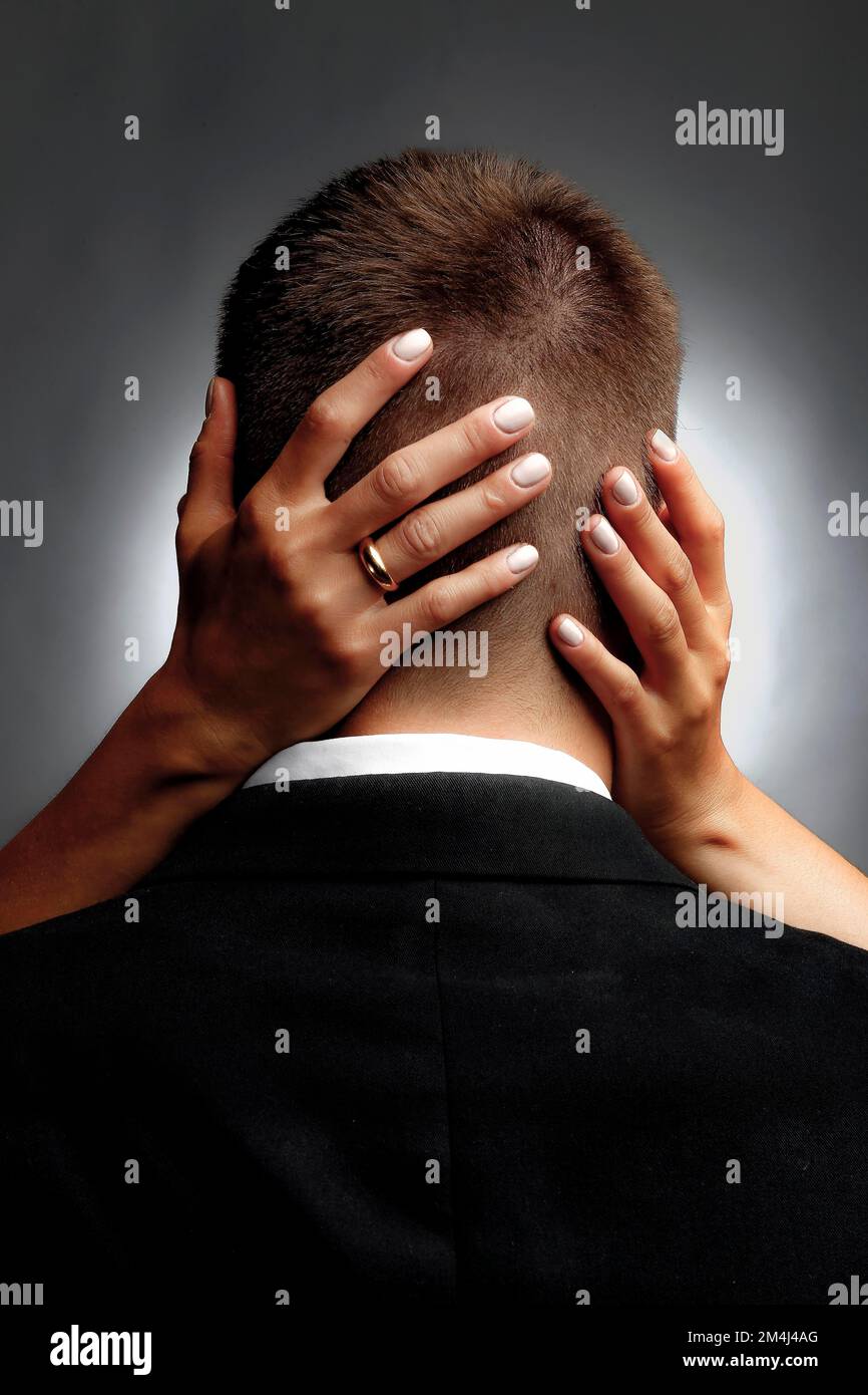 Back of head of man in suit with woman's hands. Lovers, embrace Stock Photo