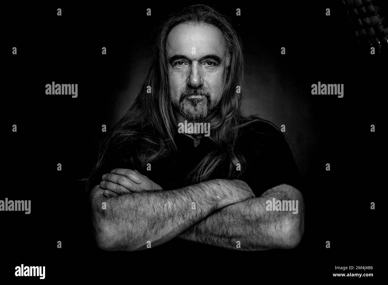 Man with long hair and hand with folded arms, black and white photo Stock Photo