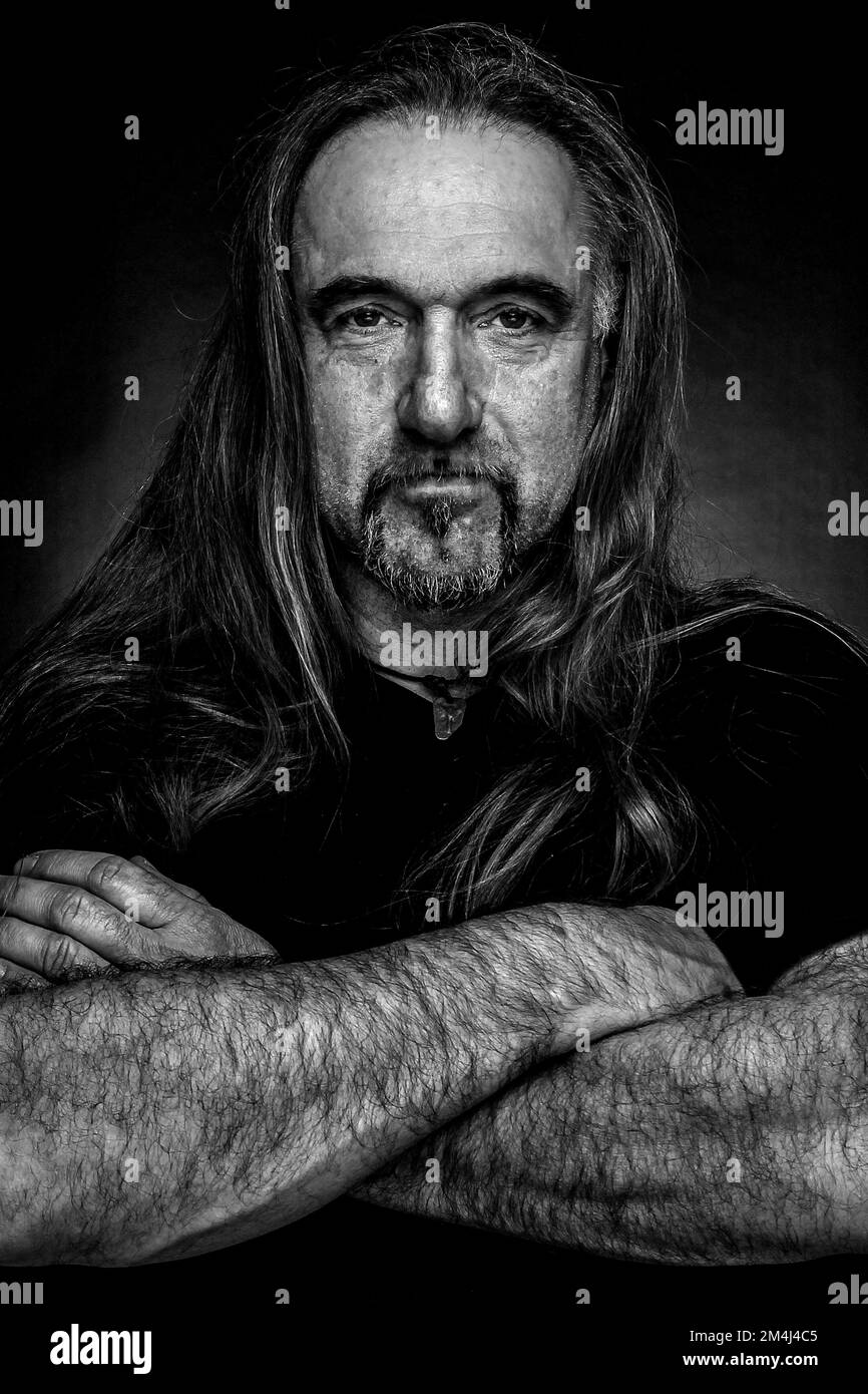 Man with long hair and hand with folded arms, black and white photo Stock Photo