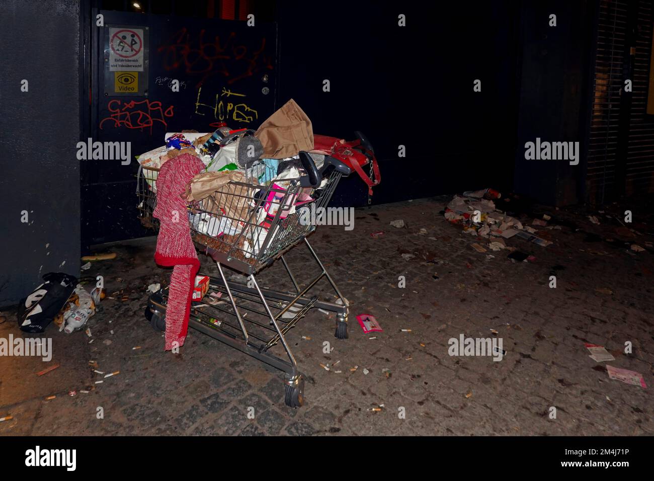 Dirty, littered pavement and a shopping trolley filled with rubbish